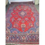 A 20thC Middle Eastern bordered carpet with a central medallion, in red and blue, 340cm x 224cm.