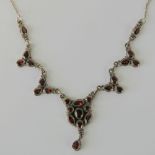 A silver and garnet necklace seven panels encrusted with various faceted cuts of garnet in rubover