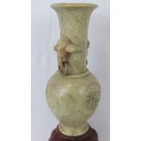A heavy soapstone baluster vase with elephant head side handles raised over a four footed rouge