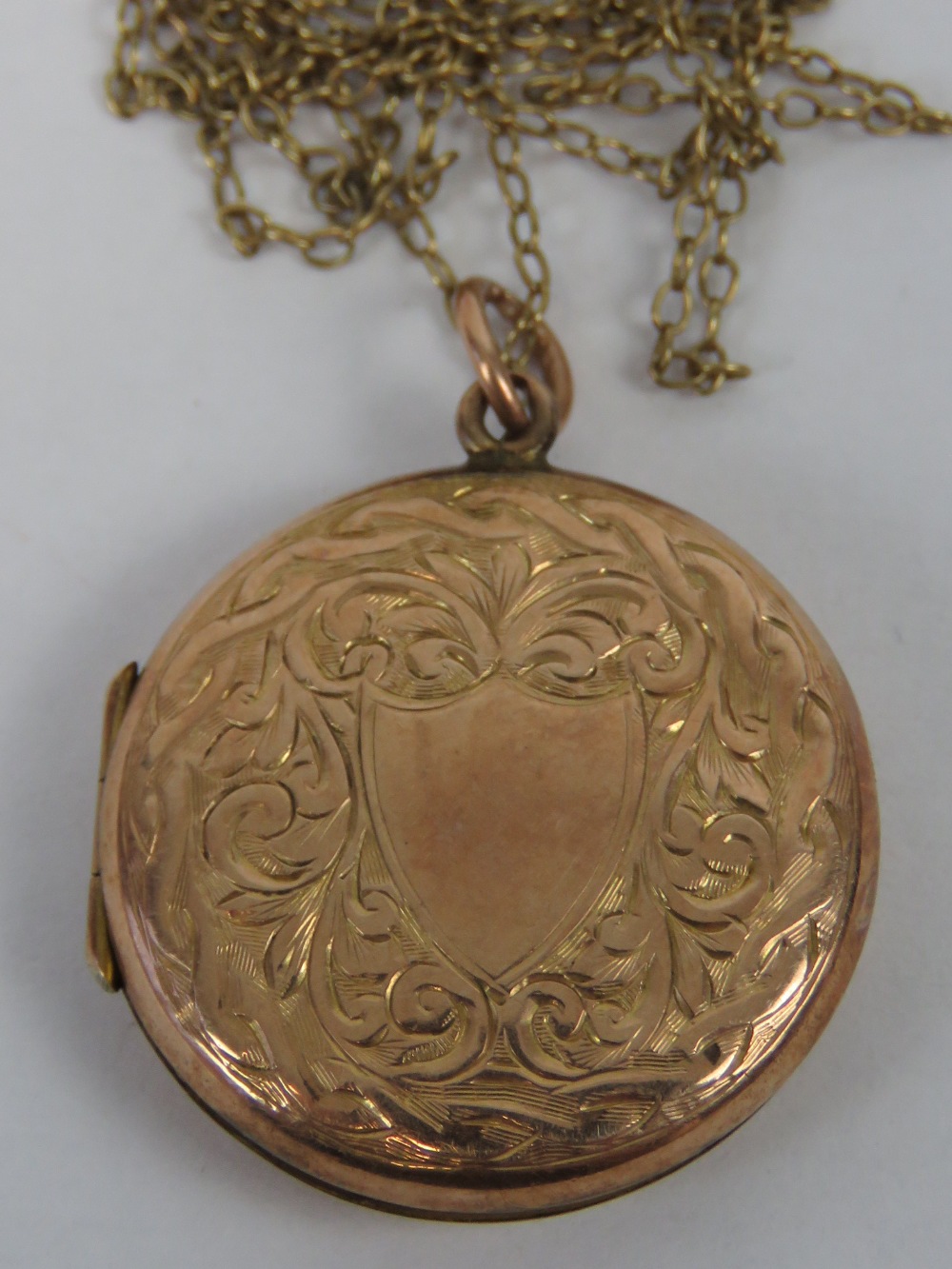 A 9ct rose gold plated locket of circular form having floral engraving and opening to reveal photo