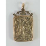 A Victorian rose metal rectangular locket having scrollwork and bale over,