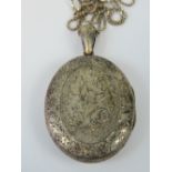 A large white metal locket having floral engraving to front and monogram to back,