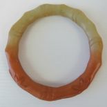 A Chinese carved and unpolished celadon and red jade bangle, approx 9.5cm outer dia, approx 7.