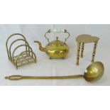 A brass kettle raised over ball feet with ceramic handle together with a large brass ladle,