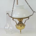 A hanging brass oil lamp style light fitting with opaque glass shade and chimney.