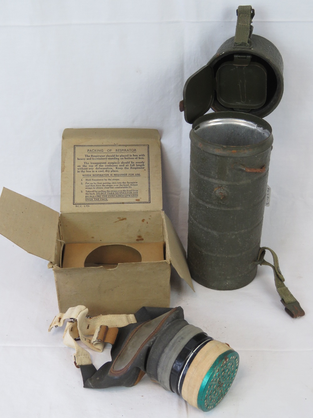 A German cylindrical gas mask cannister, together with a British WWII childs gas mask,