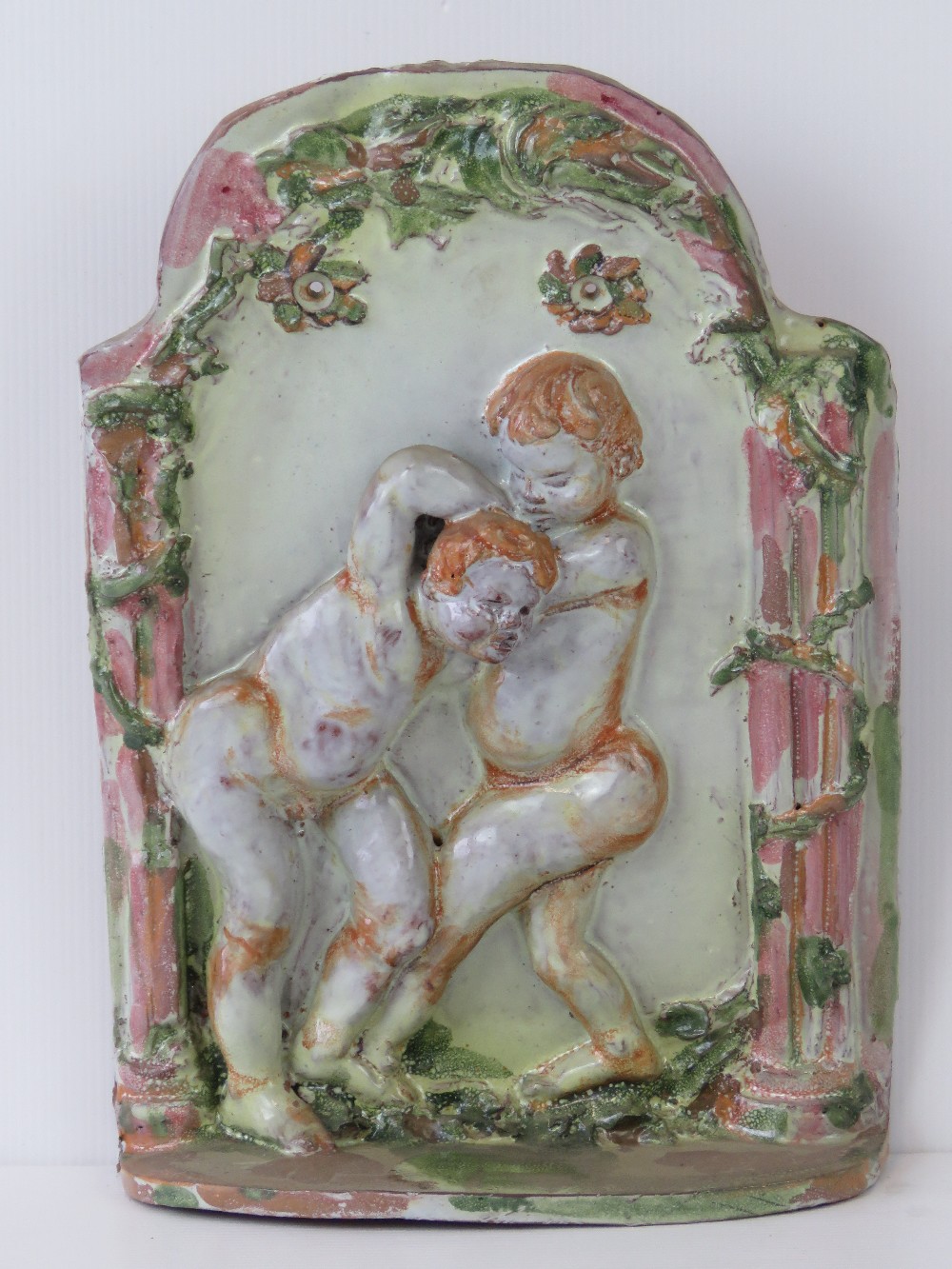 A ceramic wall plaque featuring boys fig
