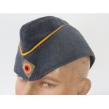 An East German blue cloth side cap havin