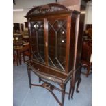 AN EDWARDIAN MAHOGANY GLAZED BOOKCASE ON SERPENTINE FRONT STAND. W.107 x H.196cms.