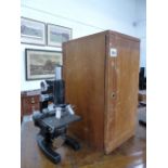 A BAUSCH & LOMB BLACK LACQUERED MONOCULAR MICROSCOPE WITH A MAHOGANY CASE.