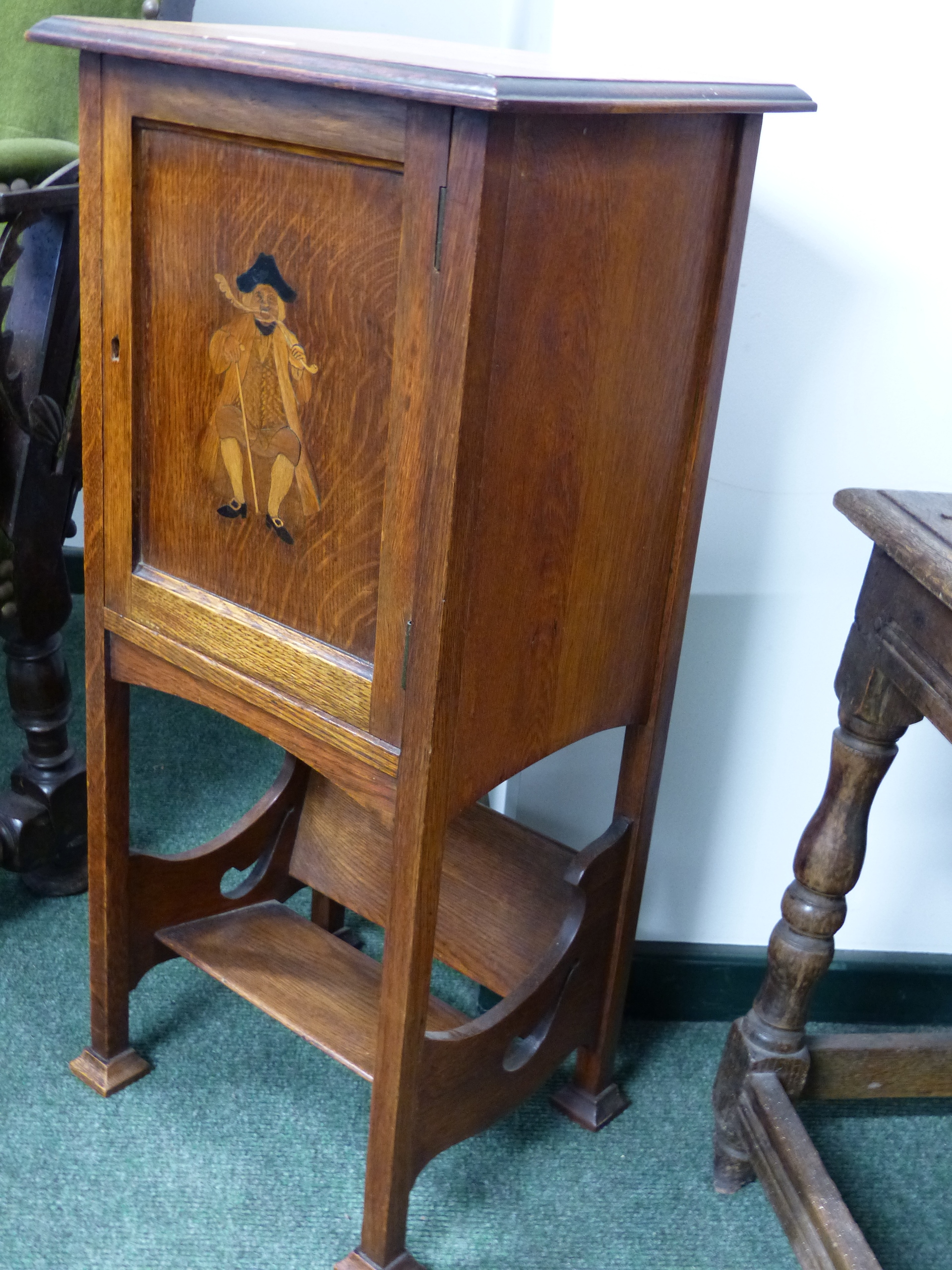 AN ARTS AND CRAFTS SMALL OAK SMOKER'S CABINET WITH BOOK TROUGH BELOW.