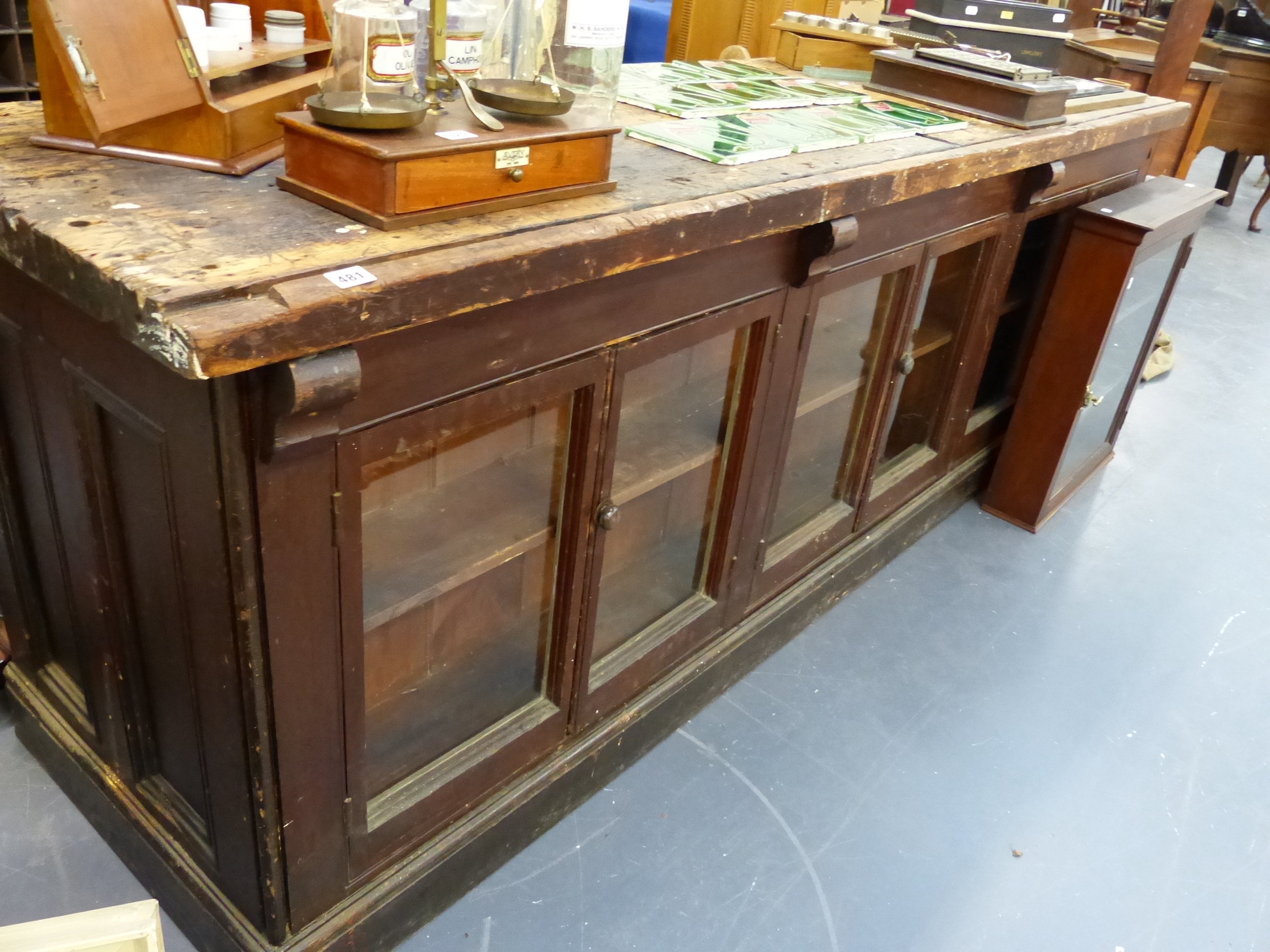 AN ANTIQUE PINE SHOP COUNTER WITH SIX GLAZED PANEL DOORS ENCLOSING SHELVES. W.244 x D.68 x H.83cms.