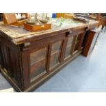 AN ANTIQUE PINE SHOP COUNTER WITH SIX GLAZED PANEL DOORS ENCLOSING SHELVES. W.244 x D.68 x H.83cms.