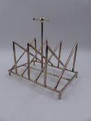 A SILVER PLATED TOAST RACK IN THE MANNER OF CHRISTOPHER DRESSER.