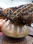 A LARGE EASTERN COPPER VESSEL WITH HAMMERED DECORATION TOGETHER WITH A SMALL PERSIAN TRIBAL MAT.