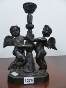 A SMALL BRONZE CANDLESTICK WITH CHERUB SUPPORTS.