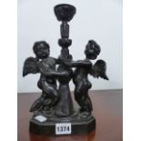 A SMALL BRONZE CANDLESTICK WITH CHERUB SUPPORTS.