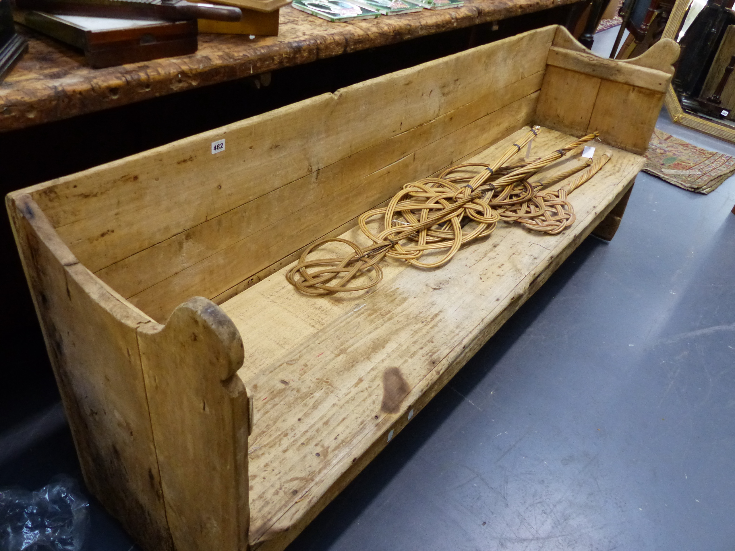 AN ANTIQUE PINE RUSTIC HALL BENCH WITH SHAPED ARMS. W.198cms.