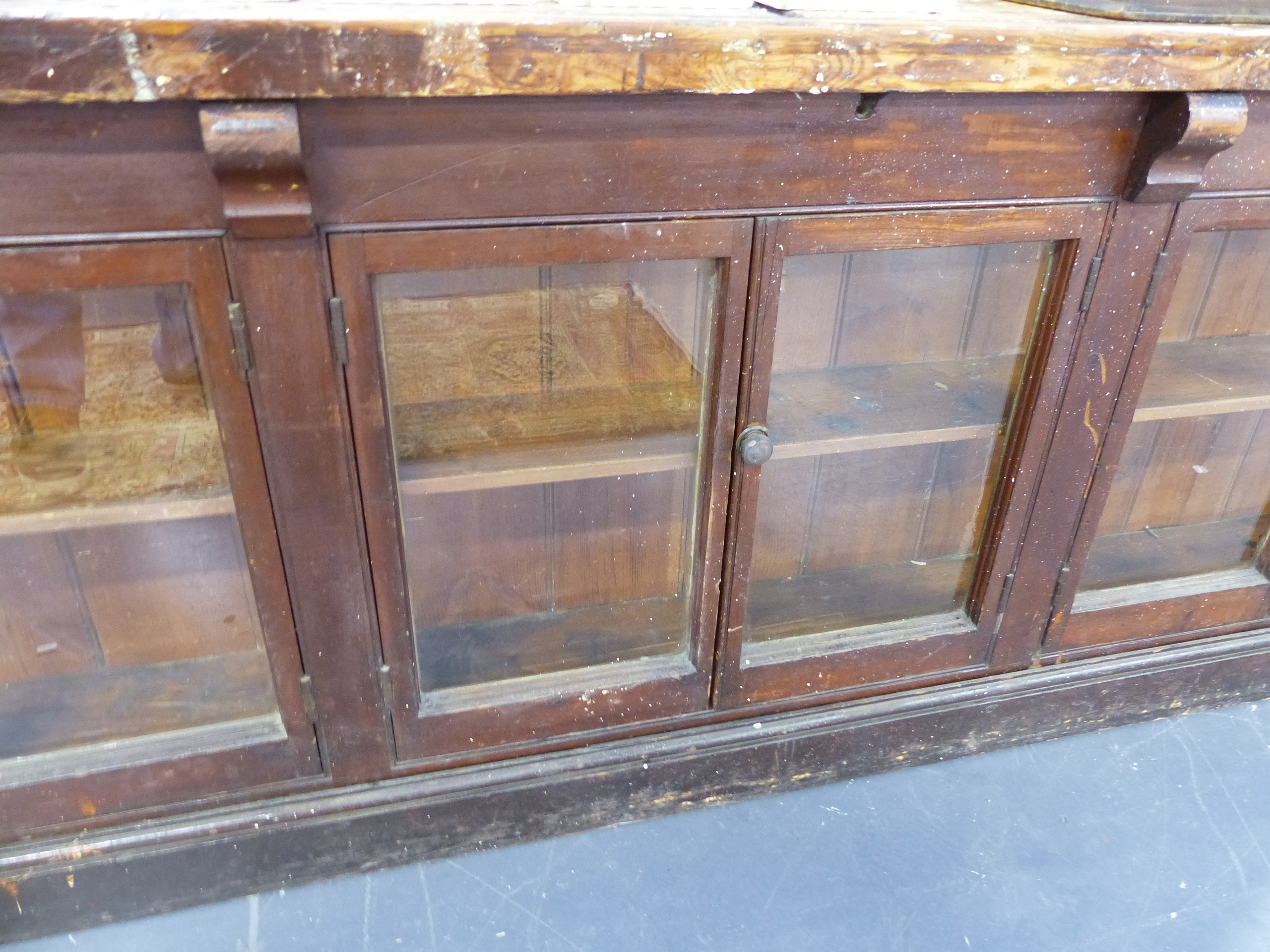 AN ANTIQUE PINE SHOP COUNTER WITH SIX GLAZED PANEL DOORS ENCLOSING SHELVES. W.244 x D.68 x H.83cms. - Image 5 of 16