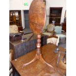 AN EARLY YEW WOOD TILT TOP LAMP TABLE ON TRIPOD SUPPORTS.