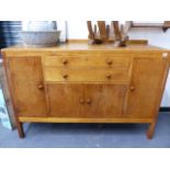 A HEAL'S GOLDEN OAK SIDEBOARD WITH TWO CENTRAL DRAWERS OVER CUPBOARD DOORS WITH TURNED WOODEN