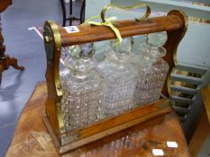 AN EDWARDIAN OAK AND BRASS MOUNTED THREE BOTTLE TANTALUS.