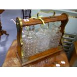 AN EDWARDIAN OAK AND BRASS MOUNTED THREE BOTTLE TANTALUS.