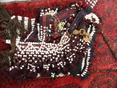 AN EASTERN TRIBAL HORSE HARNESS AND SADDLE BAG SEWN WITH SHELL BEADS AND BUTTONS.