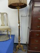 A GEORGIAN STYLE CARVED PAINTED AND GILTWOOD FLOOR LAMP WITH A FRINGED VINTAGE SHADE.