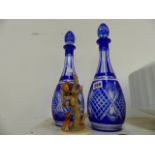 A PAIR OF CUT GLASS DECANTERS AND A HUMMLEE FIGURINE.