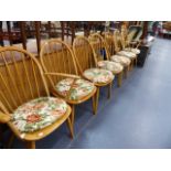 AN ERCOL EXTENDING DINING TABLE AND SEVEN ERCOL DINING CHAIRS.