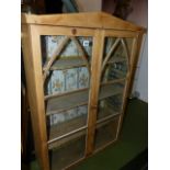 A GLAZED PINE CABINET.