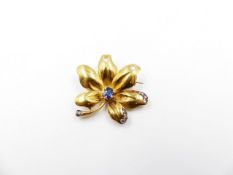 A PRECIOUS YELLOW METAL TESTED AS GOLD SAPPHIRE AND DIAMOND FLOWER BROOCH. THE CENTRAL OVAL SAPPHIRE