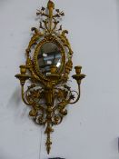 A PAIR OF CARVED GILTWOOD NEOCLASSICAL STYLE OVAL MIRROR BACK THREE LIGHT WALL SCONCES. H.95cms.
