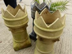 A GROUP OF THREE CASTELLATED LARGE CHIMNEY POTS AND A SMALLER TERRACOTTA CHIMNEY POT.