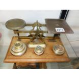 A VINTAGE SET OF BRASS POSTAGE SCALES AND VARIOUS WEIGHTS ON AN OAK BASE.