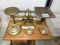 A VINTAGE SET OF BRASS POSTAGE SCALES AND VARIOUS WEIGHTS ON AN OAK BASE.