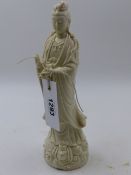 A CHINESE BLANC DE CHINE FIGURE OF A STANDING DEITY ON A WAVE DECORATED BASE. H.24cms.