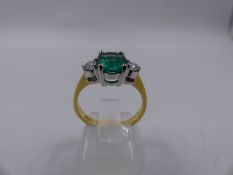 A 585 STAMPED PRECIOUS YELLOW METAL EMERALD AND DIAMOND THREE STONE RING. THE CENTRAL STONE BEING AN