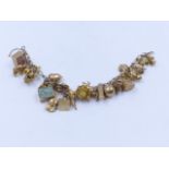A 9ct YELLOW GOLD CHARM BRACELET COMPLETE WITH VARIOUS CHARMS TO INCLUDE A ROMANY WAGON, GOLF