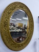 A LATE 19th.C.GILT NEOCLASSICAL STYLE OVAL MIRROR, BEVEL PLATE WITH SCROLLING FOLIATE SURROUND. H.