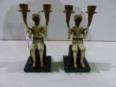 A PAIR OF DECORATED TWIN LIGHT PAINTED BRONZE CANDELABRA IN THE FORM OF SEATED BLACKAMOORS WITH
