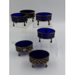 A SET OF SIX GEORGE III OVAL PIERCED SALTS COMPLETE WITH BLUE GLASS LINERS. DATED LONDON 1795.