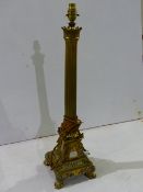 A GILT BRONZE FRENCH EMPIRE STYLE COLUMN FORM LAMP BASE WITH EAGLE CORNER PLINTH RESTING ON PAW