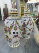 A PAIR OF CONTINENTAL RIBBED OVOID VASES WITH COVERS PAINTED WITH FLOWERS AND INSECTS. H.24cms.