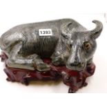 A CHINESE GREEN GLAZED FIGURE OF A RECUMBENT WATER BUFFALO ON CONFORMING CARVED HARDWOOD STAND. W.