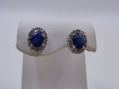 A PAIR OF WHITE METAL SAPPHIRE AND DIAMOND STUD EARRINGS. EACH OVAL SAPPHIRE IS SUSPENDED IN A