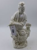 A CHINESE BLANC DE CHINE FIGURE OF A DEITY SEATED ON A ROCK WORK BASE HOLDING A SCROLL. H.38cms.