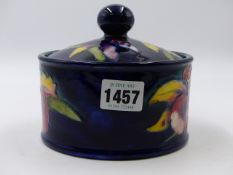 A MOORCROFT POTTERY LIDDED CYLINDRICAL JAR PAINTED WITH FLOWERS. 14cms DIAMETER. H.11.5cms.