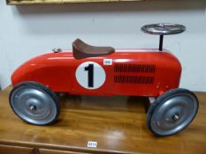 A VINTAGE CHILD'S TIN PLATE SIT ON MODEL RACING CAR.